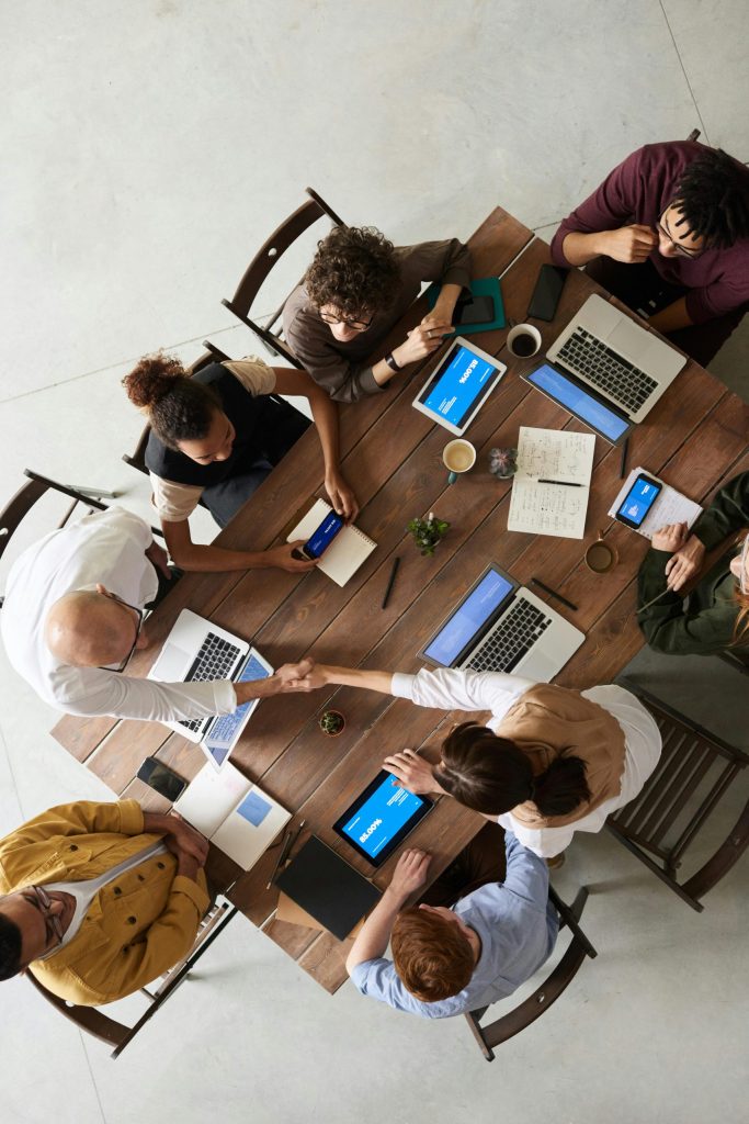 Top view of a diverse team collaborating in an office setting with laptops and tablets, promoting cooperation.