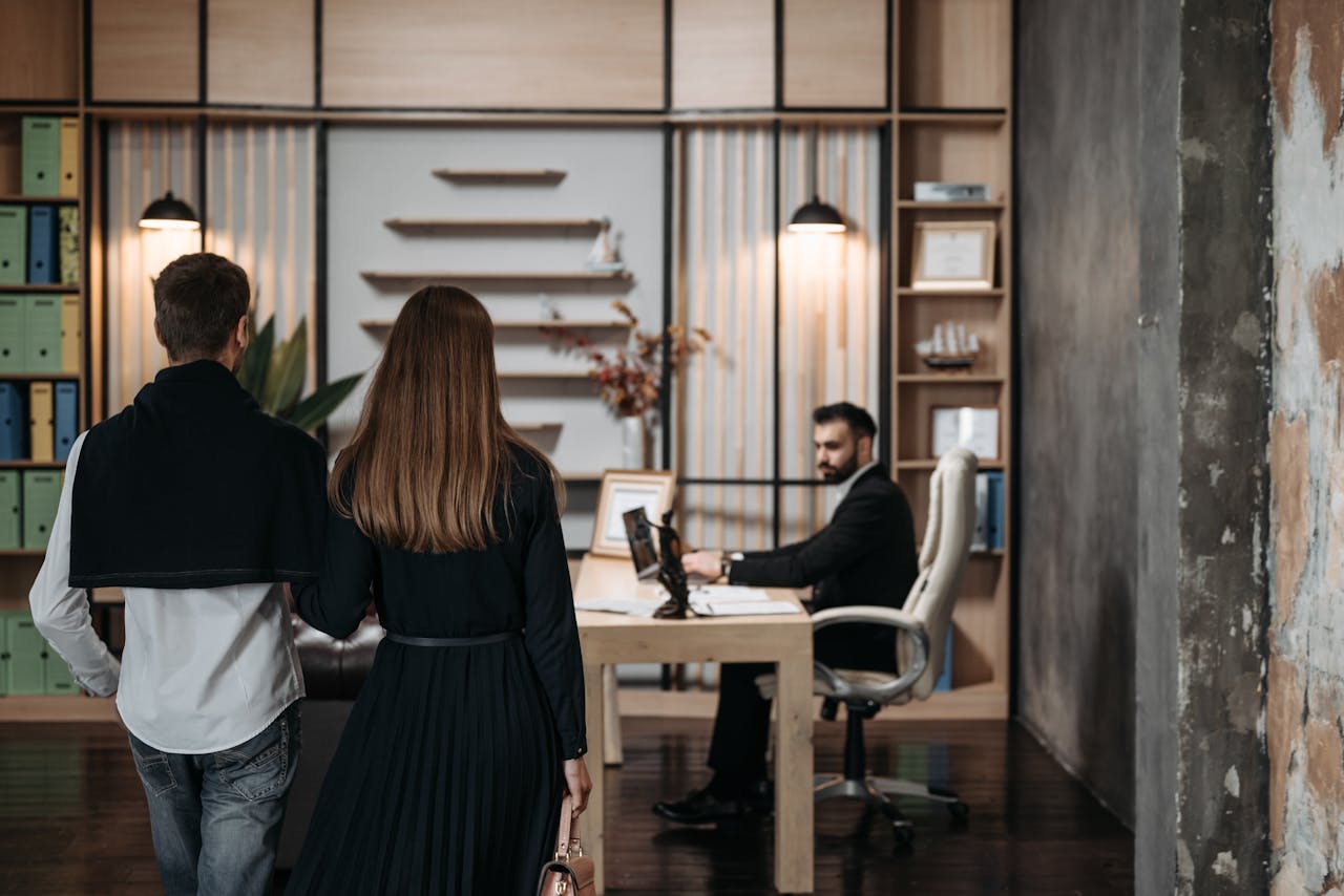 Inicio A couple approaches a lawyer in a contemporary office setting for a professional consultation.